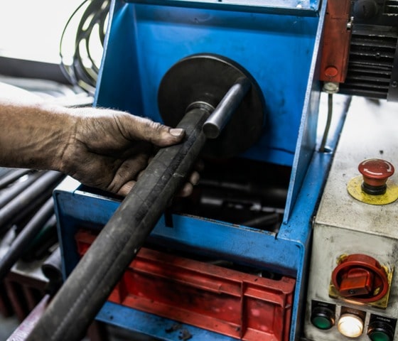 worker cutting hydraulic hoses in a metal workshop picture